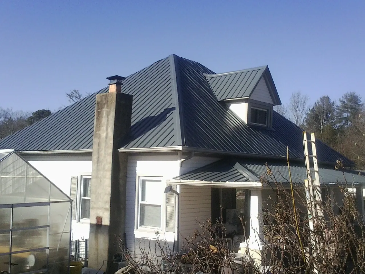 Dark blue standing seam metal roof on a white farmhouse with dormer — Slate & Tile Roof Repair by Roofing Brothers in Minooka