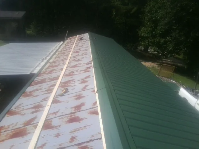 Old rusted panels beside newly installed green metal roofing — Wind Damage Roof Repair by Roofing Brothers in Minooka
