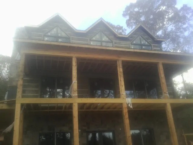 Dormers and porch framing on a large log home under construction — Roof Coating work by our crew in Minooka