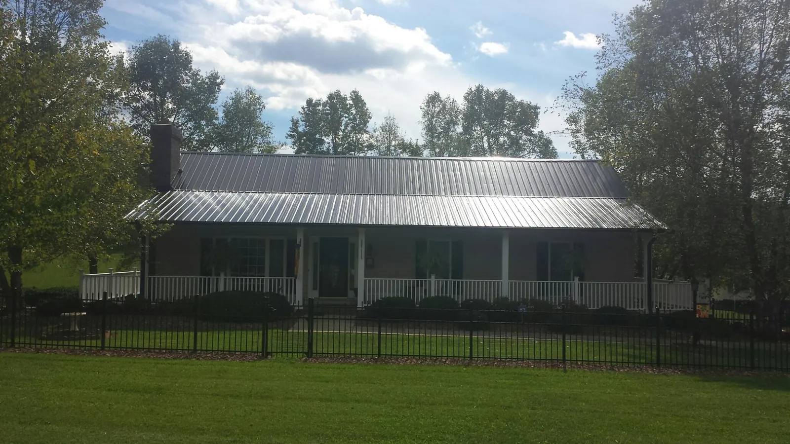 Gray metal roof on a brick ranch with a full width front porch — Gutter Guard Installation work by our crew in Minooka