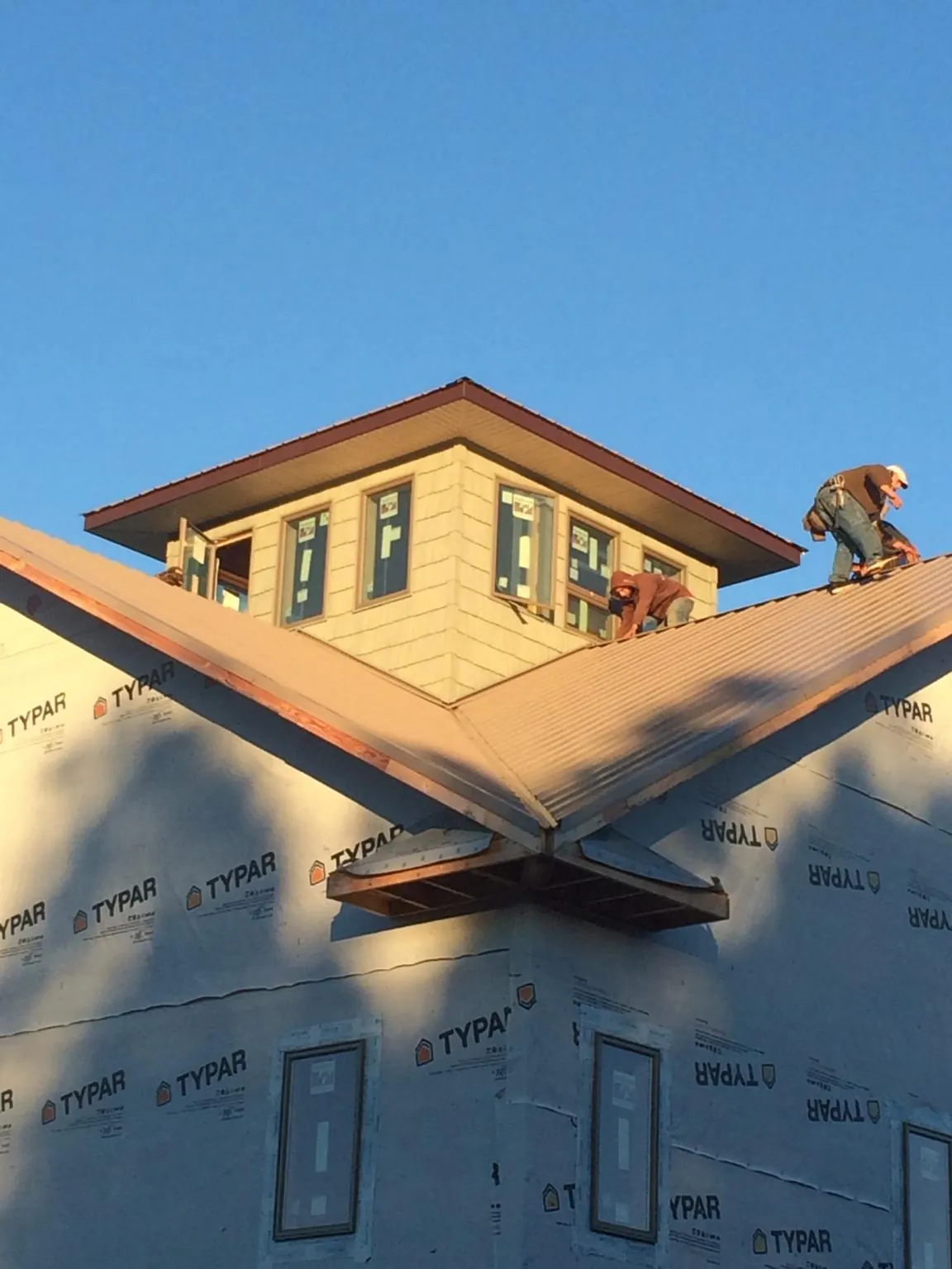 Roofers working around a rooftop cupola on a new metal roof at sunset — Roof Waterproofing in Minooka by Roofing Brothers